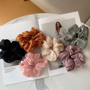 Détail de six chouchous en organza irisé aux couleurs variées posés sur un magazine