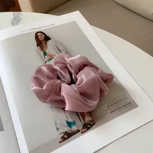 Vue détaillée d'un chouchou en satin brillant rose poudré sur un magazine de mode