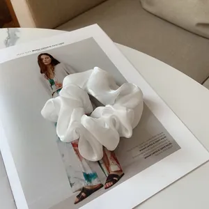 Détail macro du chouchou en organza blanc brillant avec texture de tissu plissé élégant