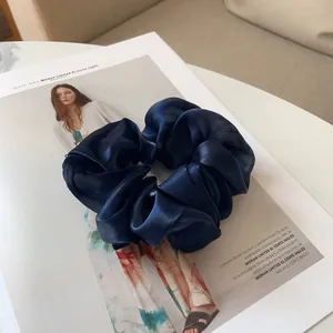 Détail macro d'un chouchou en satin bleu foncé au lustre soyeux sur un magazine