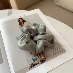 Détail d'un chouchou en satin au lustre subtil posé sur un magazine de mode