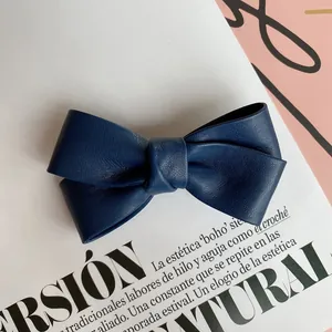 Detail of navy blue faux leather bow hair clip with elegant lychee texture and stitching