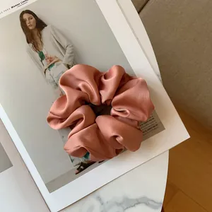 Close-up of a pink satin scrunchie with pleated texture on a fashion magazine