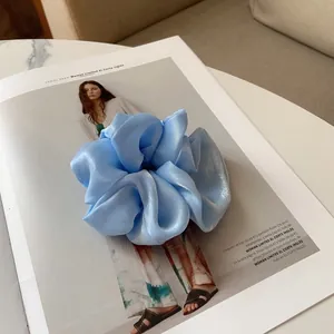 Détail d'un chouchou en satin bleu clair avec texture perlée sur un magazine de mode