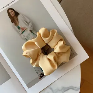 Close-up of cream satin silk scrunchie with soft pleats on a fashion magazine page