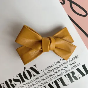 Close-up of ginger yellow bow hair clip featuring premium lychee pattern leather texture
