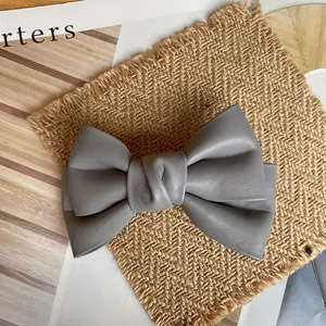 Detailed view of the grey leather bow hairpin with realistic lychee grain texture