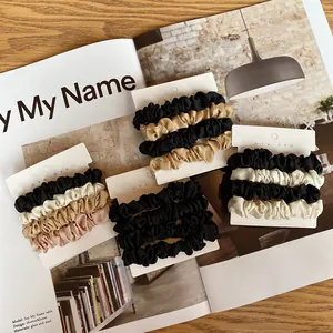Close-up of four silk satin elastic hair ties on a display card in neutral colors