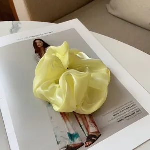 Gros plan d'un chouchou géant en satin jaune pâle brillant sur un magazine de mode