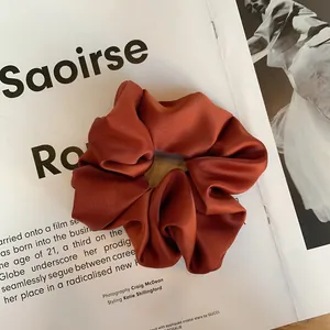 Vue détaillée d'un chouchou en satin texturé brun rouge sur un magazine de mode