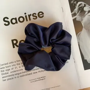 Vue détaillée d'un chouchou en satin bleu marine avec texture lisse sur magazine de mode