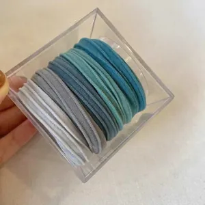 Macro shot of 5-color gradient blue elastic hair ties organized in a clear acrylic box