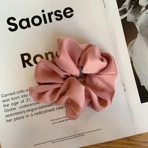 Texture détaillée du chouchou en satin plissé rose poudré sur fond de page magazine