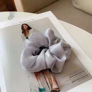 Gros plan d'un chouchou géant en satin gris argenté sur un magazine de mode