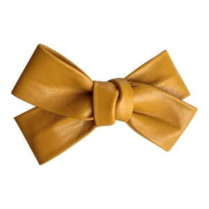 Mustard yellow faux leather bow hair clip with textured pebble grain finish