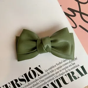 Detail of olive green leather bow hair clip with textured finish and layered design