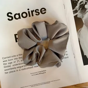 Détail du chouchou en satin gris aux reflets soyeux et aux plis élégants et doux