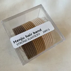 Detailed macro view of 24-piece earth tone elastic hair bands in a clear square gift box