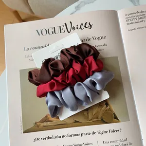 Détail de trois chouchous en soie marron rouge et gris argenté sur un magazine de mode