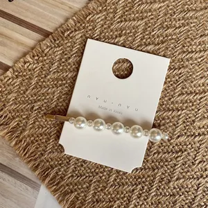 Détail de pince à cheveux élégante en perles avec base dorée sur carte de marque
