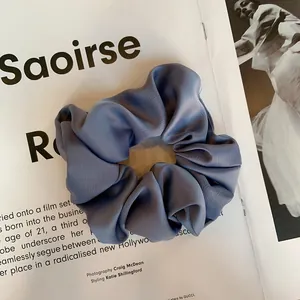 Détail d'un chouchou en satin bleu foncé avec texture subtile sur fond de magazine