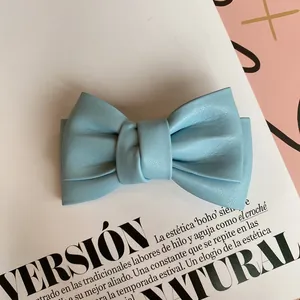 Macro shot of light blue faux leather bow hair clip with textured double-layered detail