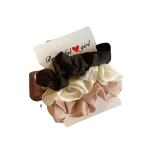 Ensemble de trois chouchous élégants en soie de couleurs noir, crème et rose champagne