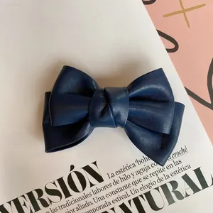 Detail of a dark blue leather bow hair clip with vintage texture on a fashion magazine