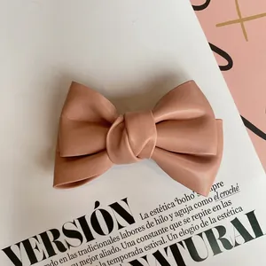 Close-up of pink faux leather bow hair clip with fine texture on magazine background