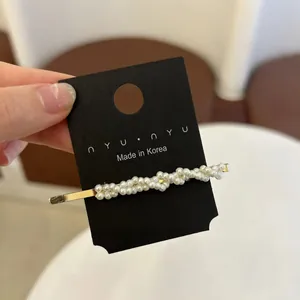 Vue détaillée d'une barrette dorée style français avec perles blanches sur carte