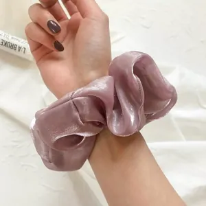 Chouchou élégant en organza mauve avec éclat métallique porté au poignet pour cheveux