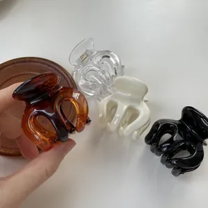 Detail view of a 4-pack hair claw clip set in transparent, amber, cream and black colors
