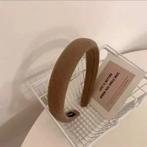 Détail d'un serre-tête en éponge marron avec étiquette faite main dans un panier