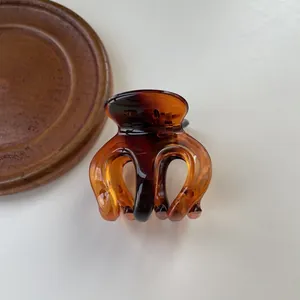 Detail view of a translucent amber tortoiseshell hair claw clip on a wooden tray