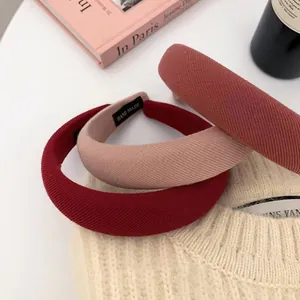 Dettaglio di cerchietti spessi in tessuto rosa vintage e rosso con etichetta fatta a mano