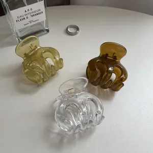 Three minimalist clear resin hair claws in amber and yellow tones on white surface