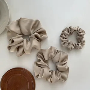 Three premium champagne satin scrunchies in various sizes with elegant silk texture