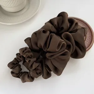 Set of two dark brown silk satin hair scrunchies displayed with elegant table decor