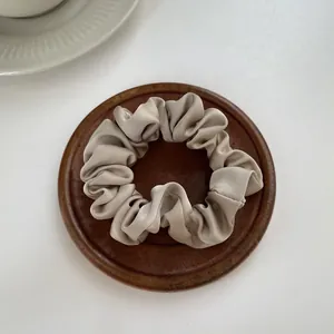 Macro detail of champagne gold satin scrunchie showing smooth silky fabric texture