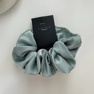 Detailed view of mint green satin scrunchie with rhinestones on black display card