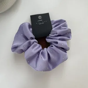 Detail of lavender satin scrunchie with sparkling rhinestones and branded tag