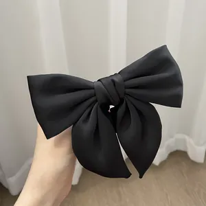 Close-up of a large black satin bow hair tie with elegant layered fabric texture