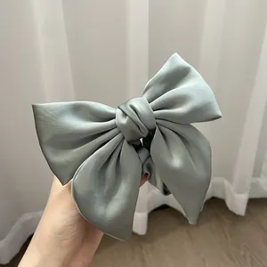 Detailed view of sage green satin bow hair tie with soft pleated texture and elegant sheen