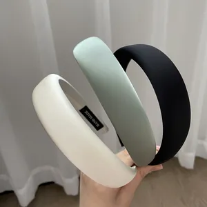 Three minimalist sponge headbands in white, green, and black with handmade label