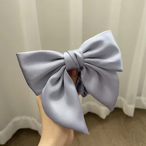 Detail of a large light blue satin bow hair tie with premium silk luster for women