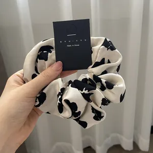 French style scrunchie with cow pattern print on smooth satin fabric held by hand