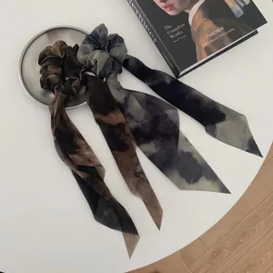 Dos gomas de pelo retro con lazo tie-dye en mesa blanca con decoración