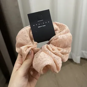 Close-up of a pink lace scrunchie with hollow floral patterns and premium fabric texture