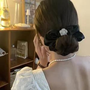 Elegante elastico in raso nero con camelia di strass scintillanti indossato da una modella