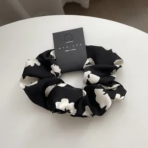 Detail view of a French style floral scrunchie with a black and white contrast pattern